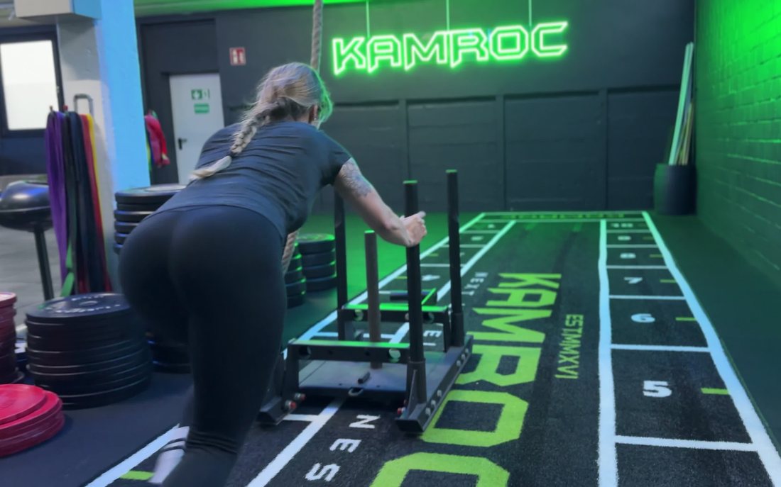 Sled-Push auf dem KAMROC-Bodengrid unterm Neon-Logo
